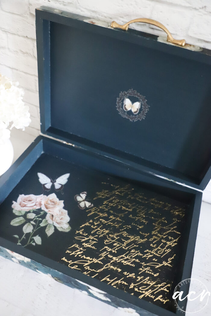 inside of box with gold script on one side, roses and butterflies on other and butterly on lid