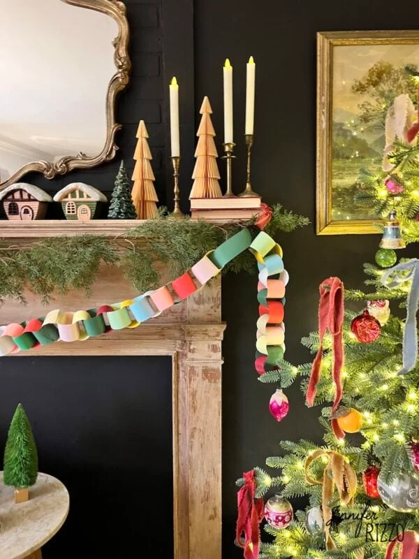 how to make an easy construction paper chain 7 a festive living room features a decorated mantel with candles, wooden trees, and garland, alongside a christmas tree with lights and colorful ornaments.