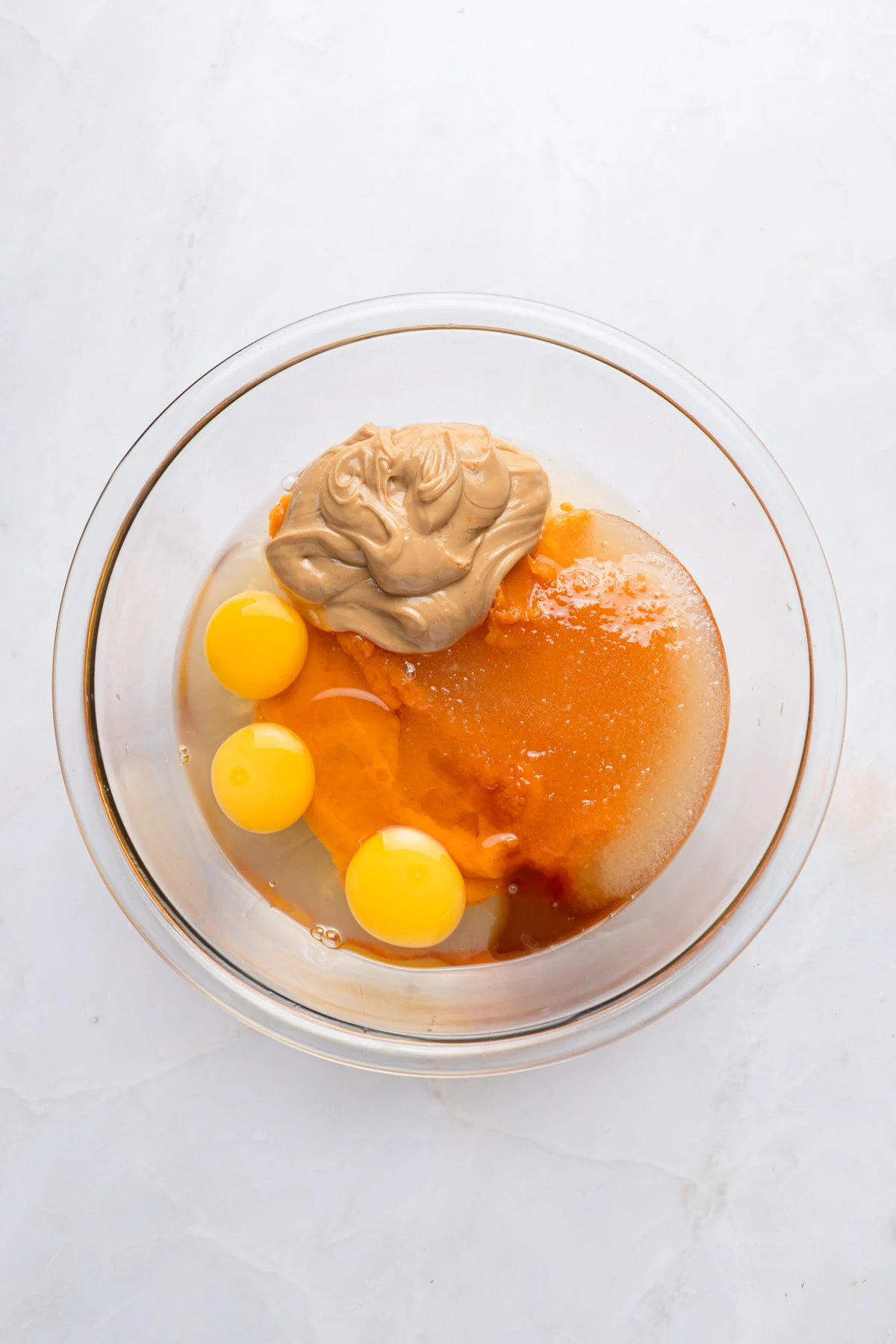 sweet potato brownies paper and stitch 4 ingredients in a bowl for brownies, including eggs, peanut butter, sweet potato, and more