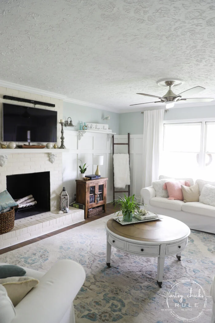 evolution of a living room 11 fireplace, round coffee table, white curtains, blue rug, white couch