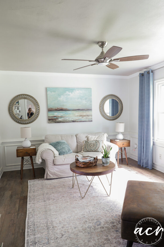 artwork and mirrors with couch and darker painted ceiling