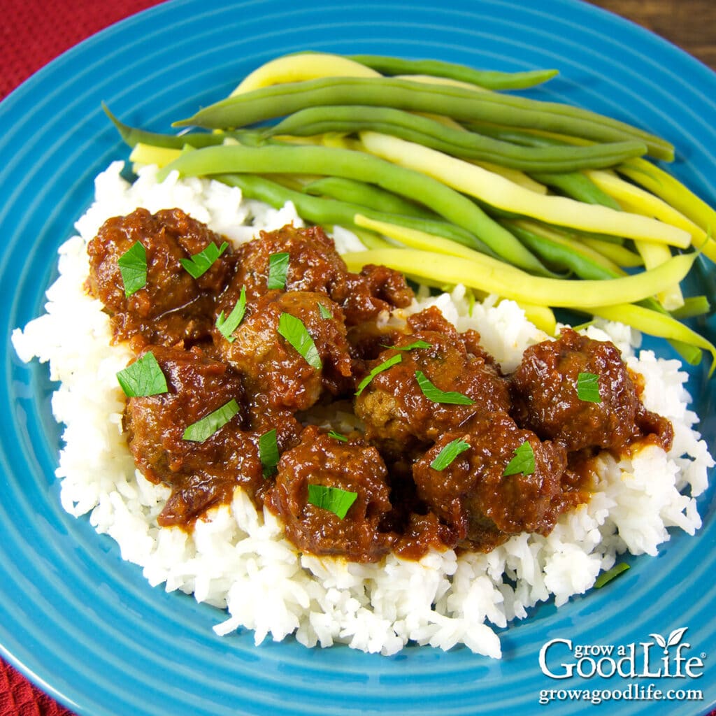 dinner plate with barbecue meatballs served over white rice and green beans.