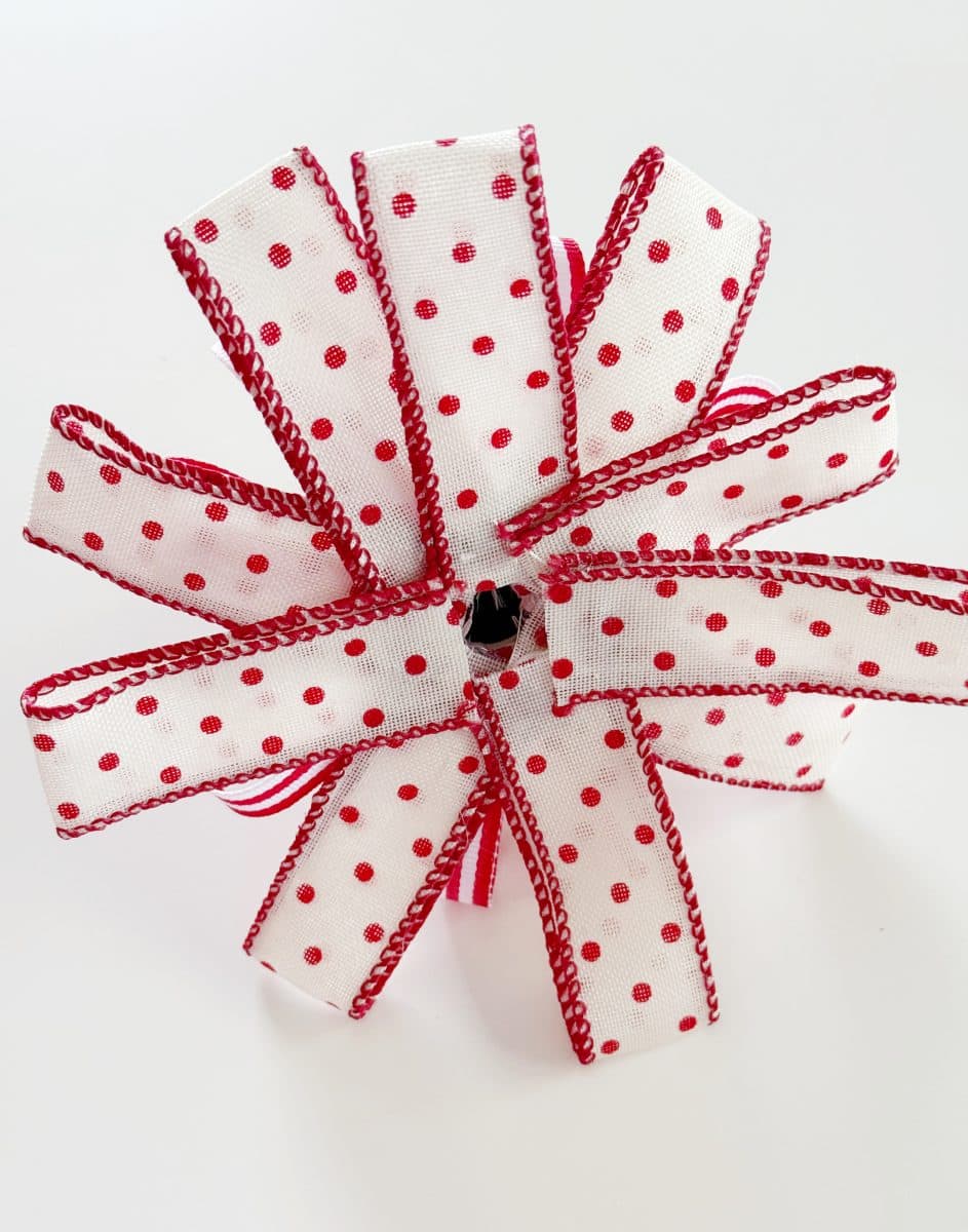 diy christmas tassel simple stepbystep tutorial 43 a decorative bow made from white ribbon with red polka dots and red edges, arranged in a flower-like shape on a white background—perfect inspiration if you're wondering how to make a giant bow.