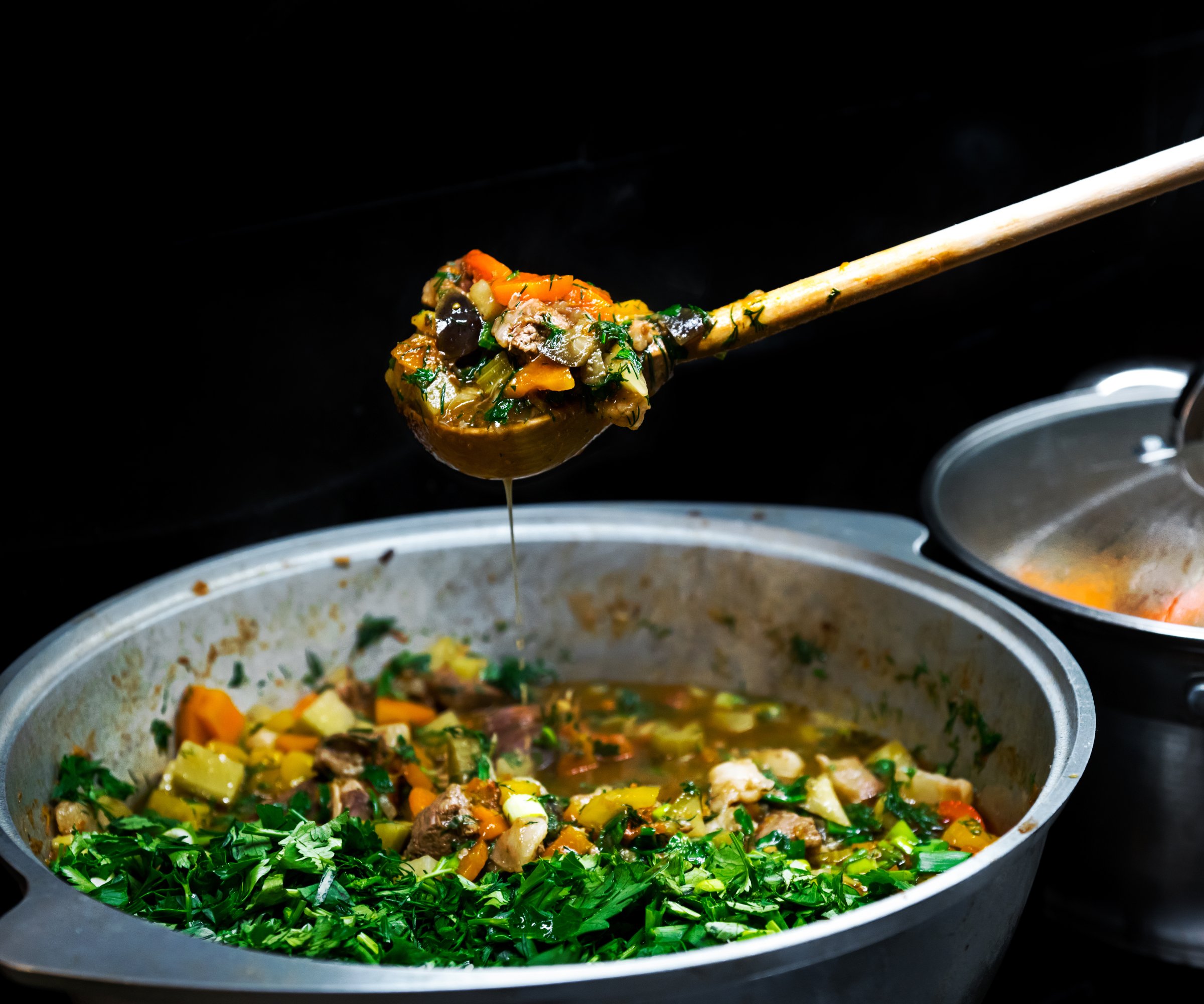 a ladle lifts a spoonful of soup above a pot