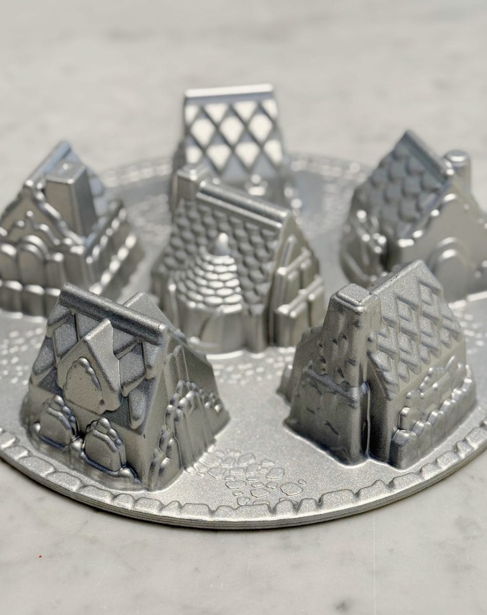 how to paint a gingerbread gift bag 24 a silver metal baking pan shaped with molds of five small houses, each featuring detailed rooftops and walls, set on a round base, placed on a light marble surface.