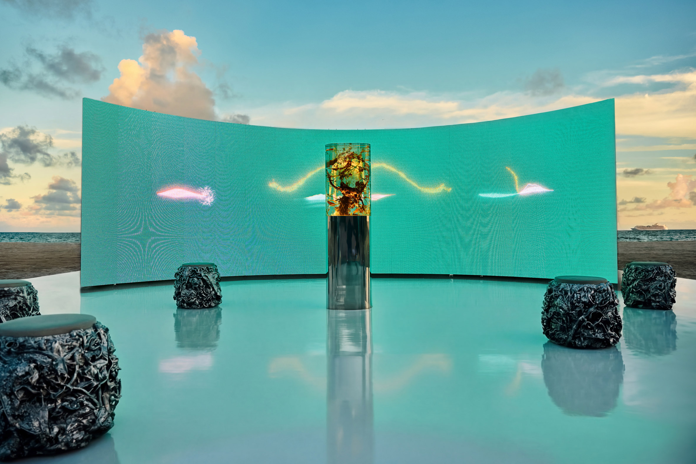 close view of marcin ruskin's resin sculpture containing botanical material set against a turquoise digital backdrop