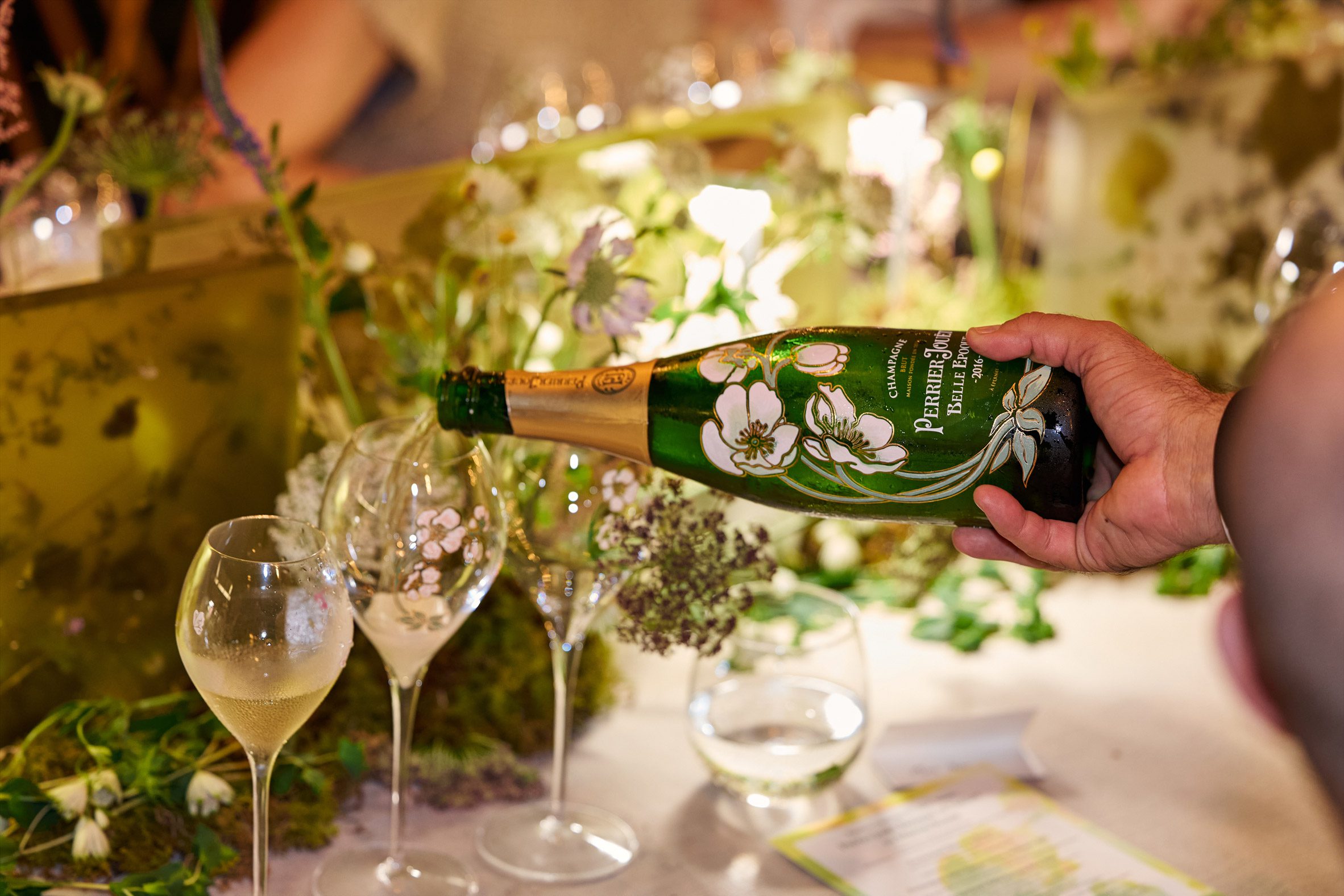 perrier-jouët champagne being poured into floral-etched glasses on a botanically decorated table
