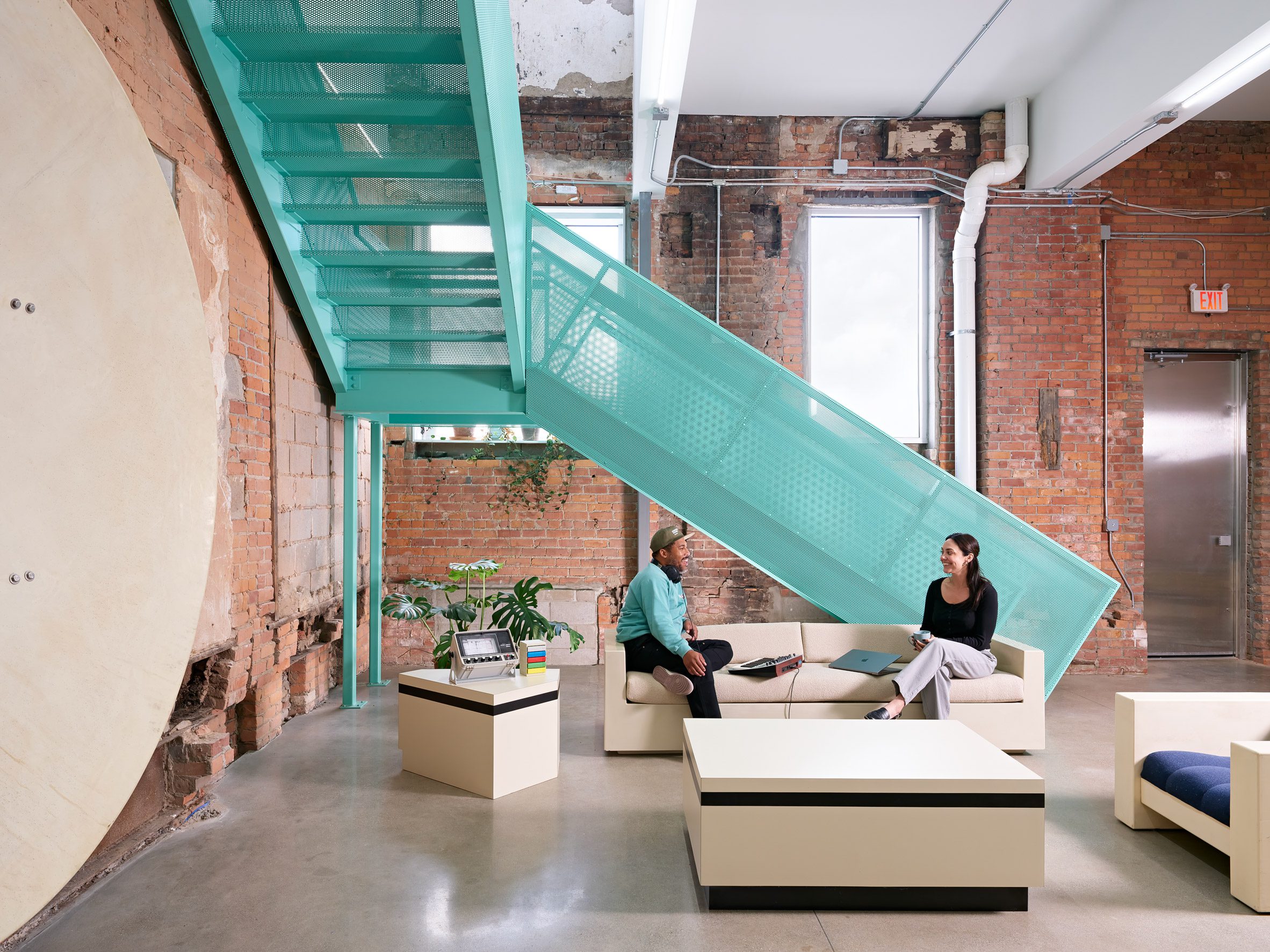 an aqua-coloured staircase in a room with an exposed brick structure
