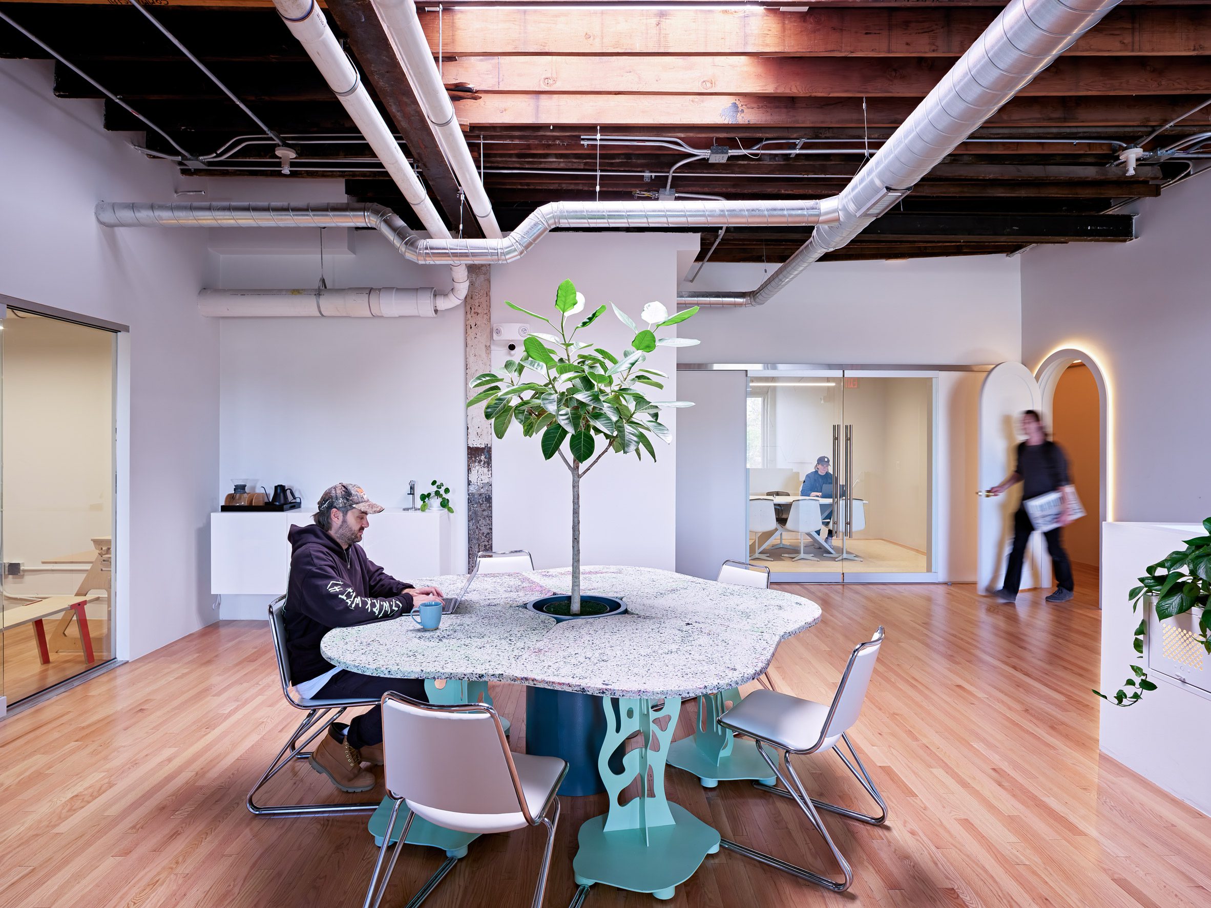 a custom table for informal work is positioned below a skylight and features a tree planted in its base