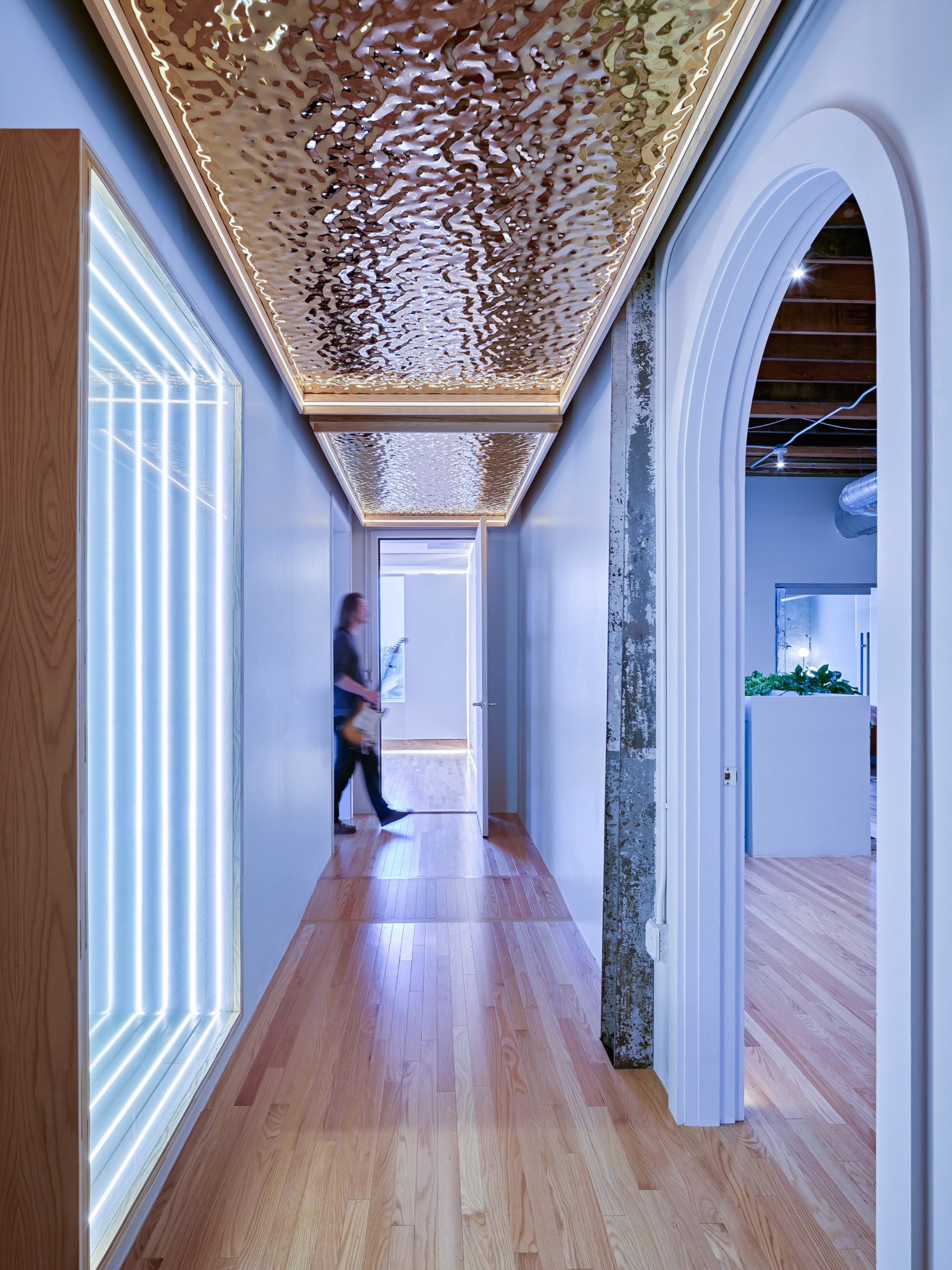 custom rippled ceiling panels and an infinity mirror decorate a hallway