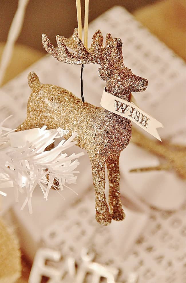 the christmas ornament that started it all 17 a glittery golden reindeer ornament with a "wish" banner hanging by a string, surrounded by festive decorations and gift wrapping materials.