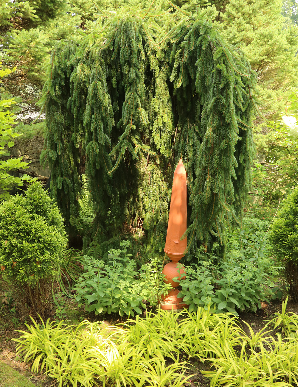 terracotta garden art in front of bright green foliage plants