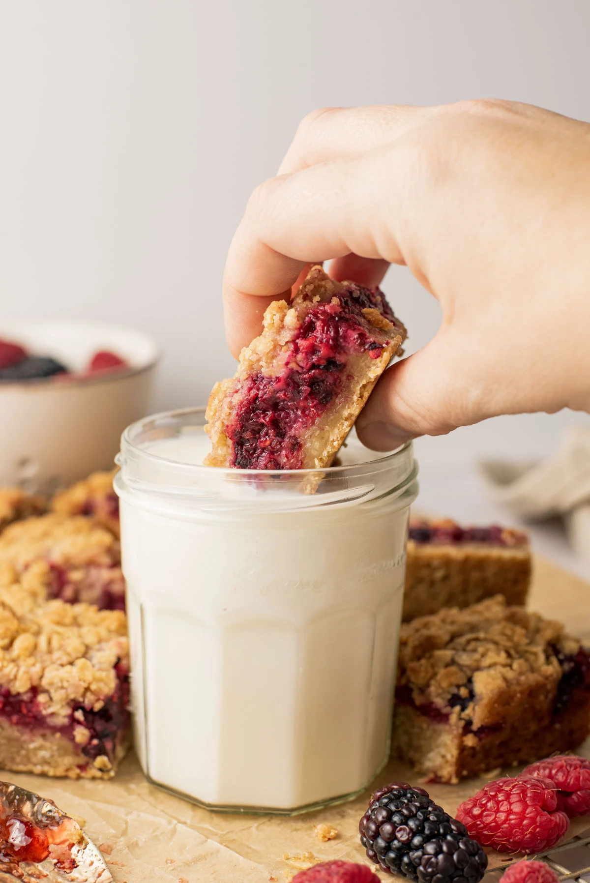 dunking shortbread bars into short glass of milk, with hands