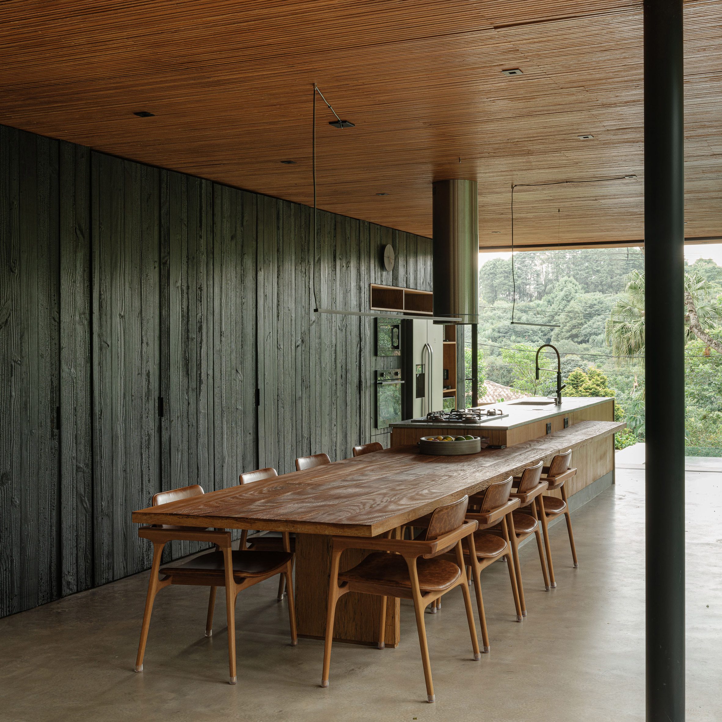 a wall of charred pine wood behind a kitchen island and dining table