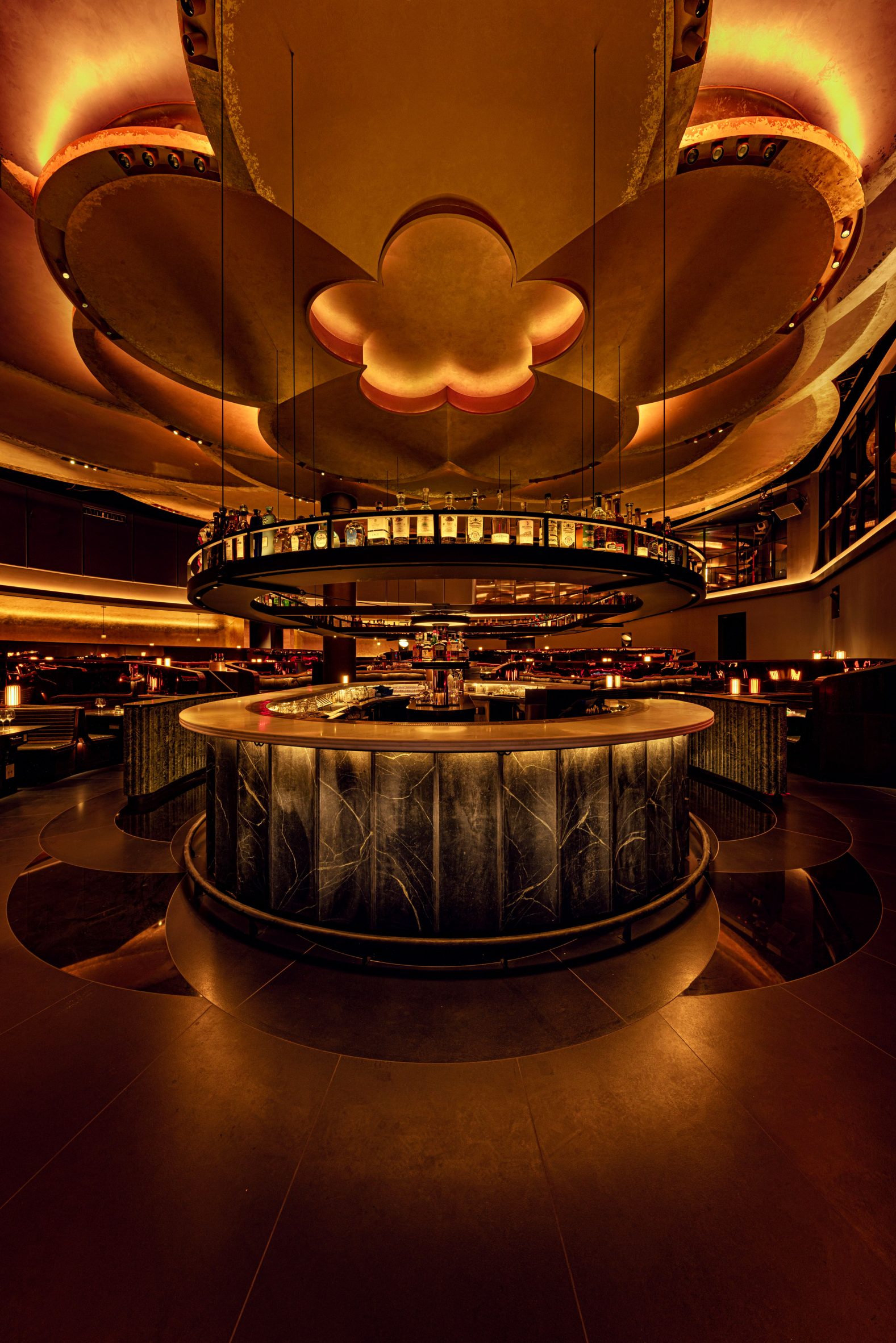 an oval-shaped bar at the centre of a restaurant, with petal-like ceiling panels overhead