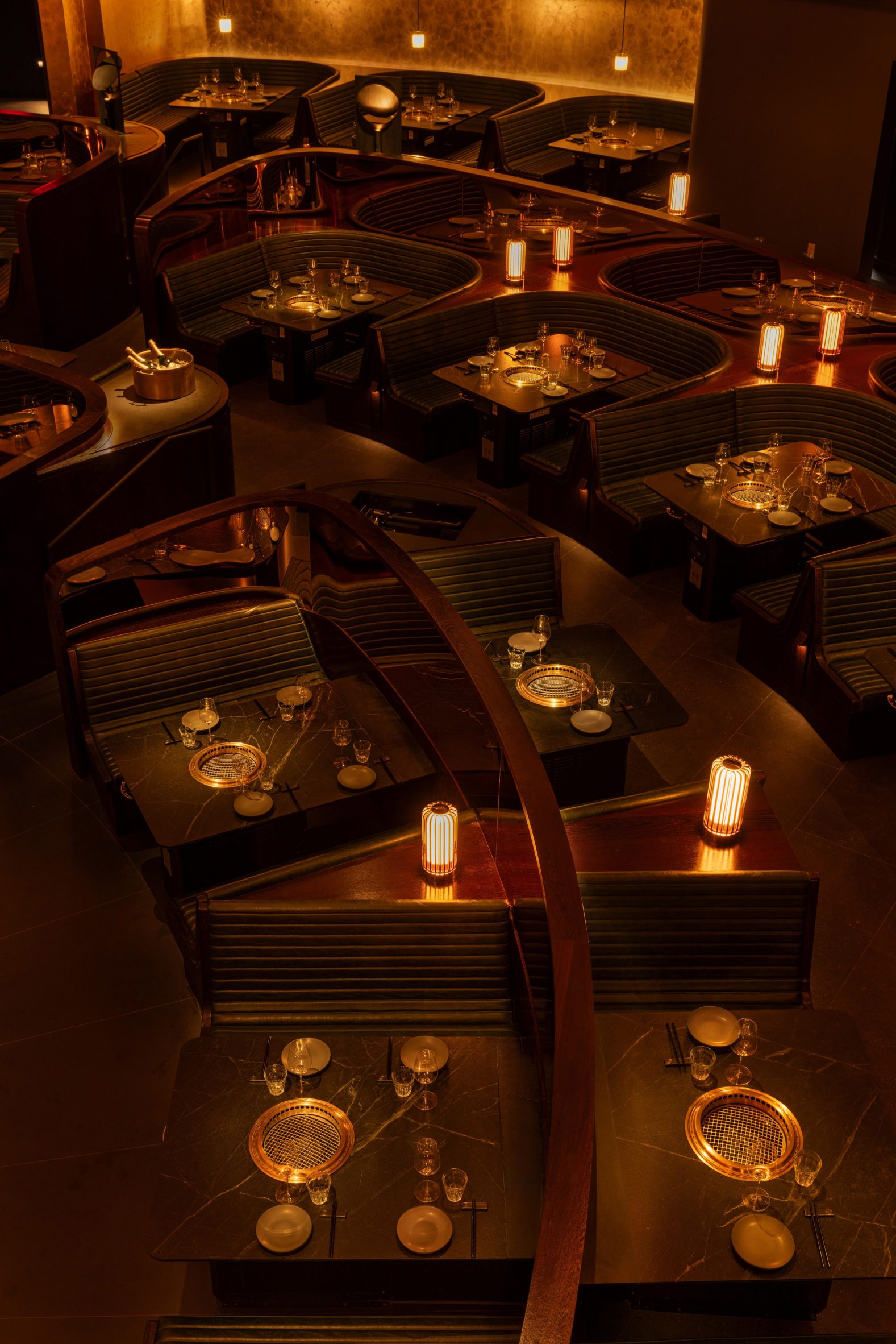 collection of ribbed leather benches and horseshoe-shaped booths surrounding black marbles tables