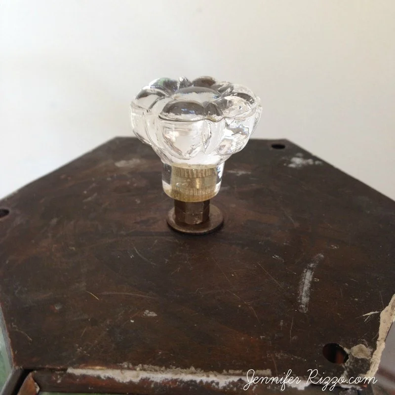 repurposed glass lamp shade cloche terrarium 1 close-up of a clear glass knob on a dark, weathered wooden surface with a small metal base, reminiscent of elements in a diy terrarium.