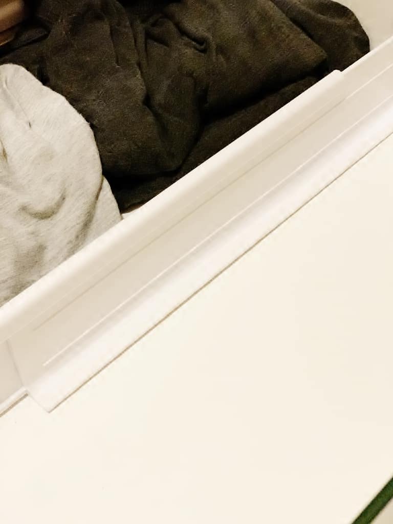 10 unexpected organizing ideas you may not have thought of 9 a partially open white drawer filled with folded clothes, showcasing an organized storage solution with various organizing products.