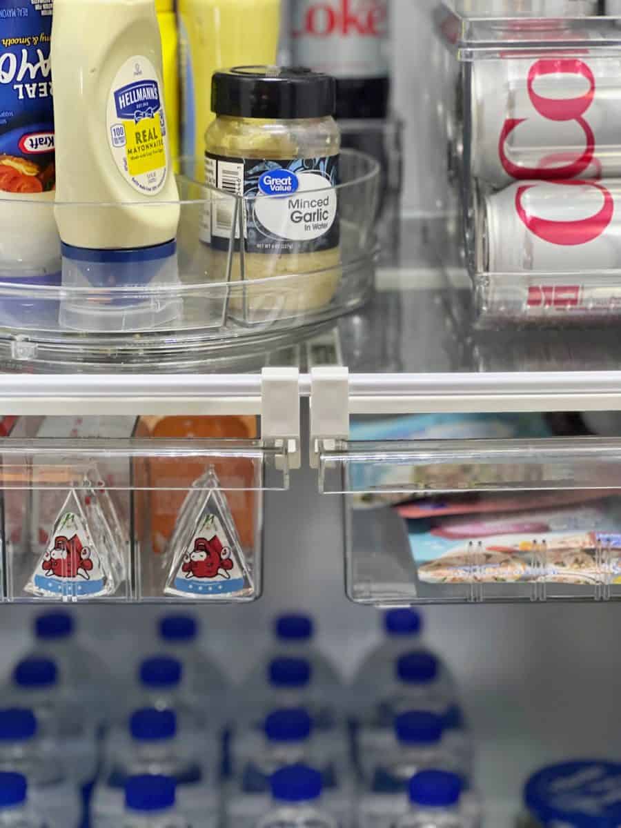 10 unexpected organizing ideas you may not have thought of 7 an open refrigerator shelf organized with products such as condiments and beverages, showcasing a variety of items including mayonnaise, minced garlic, and bottled water, with a peek of soda cans below.