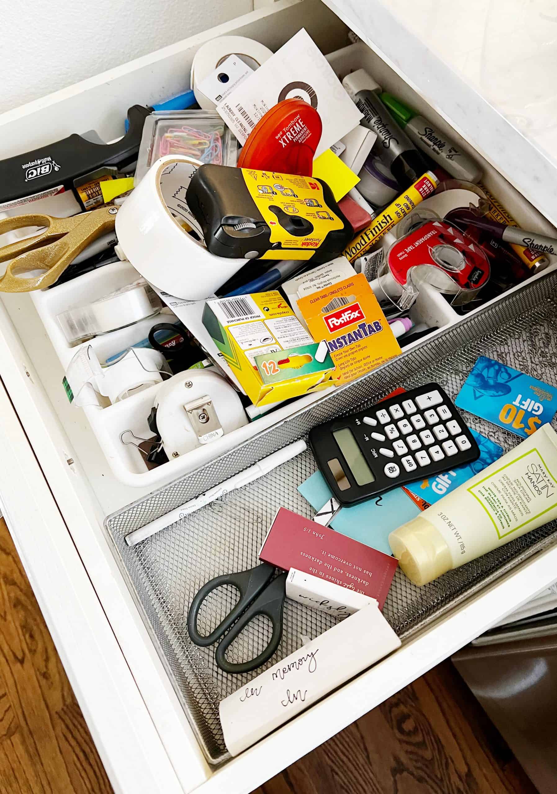 10 unexpected organizing ideas you may not have thought of 14 an open drawer overflowing with a variety of household items, including tape, scissors, calculators, and assorted stationery organizing products, exemplifying a common "junk drawer" found in many homes.