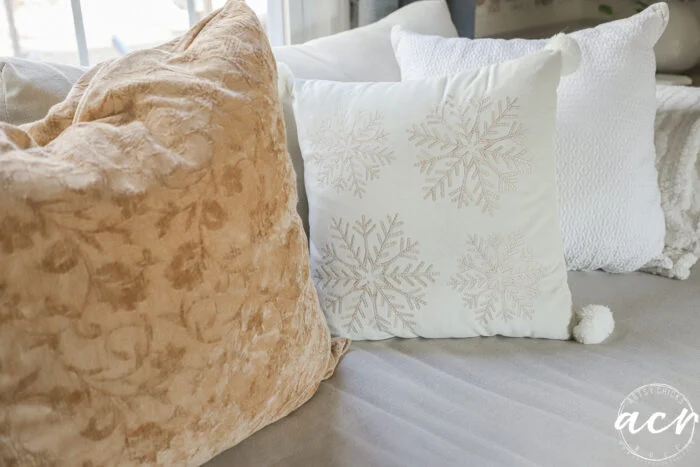 couch with mustard gold colored large pillow and snowflake pillow beside it