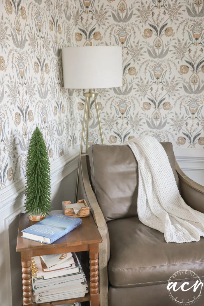 leather chair with cream colored throw and side table with tall, slim green tree