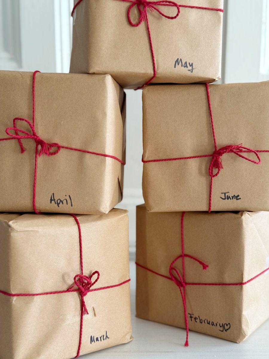 how i wake up my house 15 a collection of potted topiary plants and greenery sits on a white shelf, surrounded by wicker baskets, stacked books, and small wooden decorative houses, creating a fresh and cozy display.