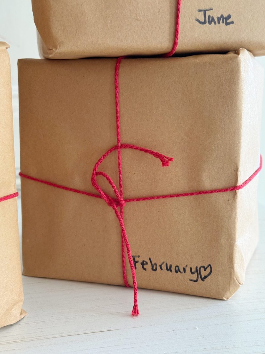 how i wake up my house 17 a glass candle warmer lamp with a gold frame and wooden base holds a candle decorated with cheerful snowmen in scarves and hats, all set on a kitchen counter with a white tile backsplash.