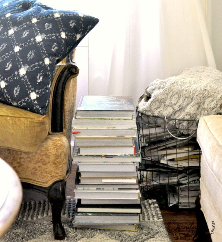different ways to use vintage books in decorating 14 in the cozy living room view, a stack of books nestles between two armchairs. one chair is adorned with a patterned pillow, adding an inviting touch, while a wire basket of blankets rests on the floor, ready to wrap you in warmth.