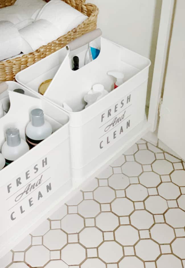 organized laundry supplies in a white storage caddy labeled "fresh and clean" in a bathroom organization, on a tiled floor.