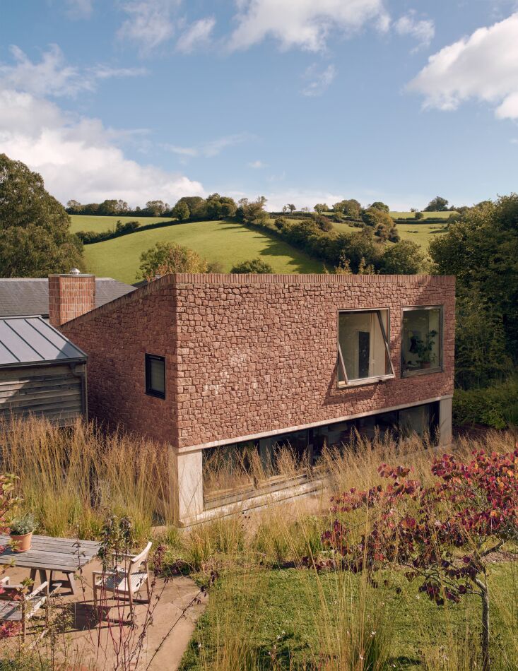 the central new building is clad in locally quarried pink sandstone edged with reclaimed brick. 