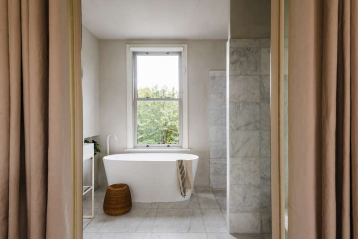 floor to ceiling blush curtains soften the look. the vintage rattan stool is by 18