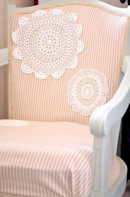 Embellishing an Upholstered Chair with Doilies 14 White wooden armchair with light pink striped upholstery, beautifully embellishing a chair with doilies on the backrest and seat for a charming, vintage touch.