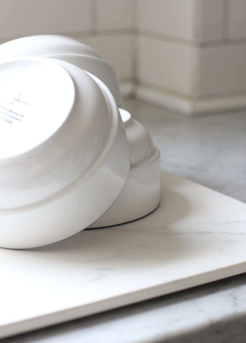 a stack of white, clean bowls on a white countertop, creating a minimalist and tidy kitchen island aesthetic.