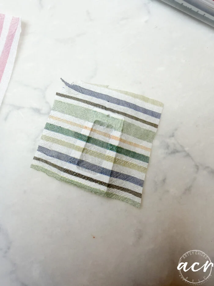 how to use uv resin and decoupage earrings 93 a small square of striped fabric with a rectangular cutout in the center, perfect for decoupage earrings or learning how to use uv resin, is placed on a white marble surface. a logo with the initials acv appears in the bottom right corner.