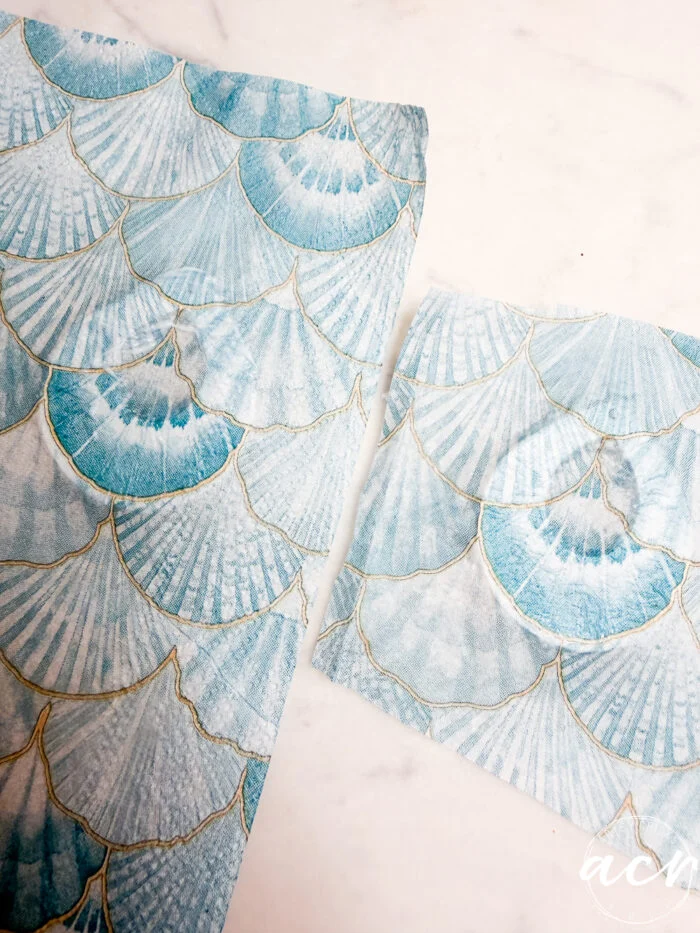 how to use uv resin and decoupage earrings 94 a sheet and a square piece of blue and white paper with a scallop shell pattern outlined in gold, perfect for decoupage earrings or learning how to use uv resin, placed on a white surface.