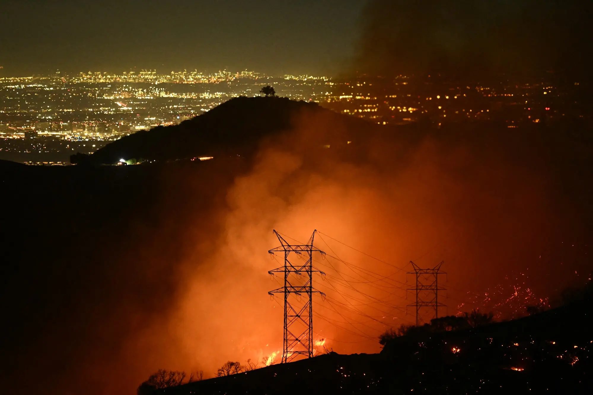 scientists have found another alarming pattern in wildfires 1 a fire rages at night with a transmission line in the foreground