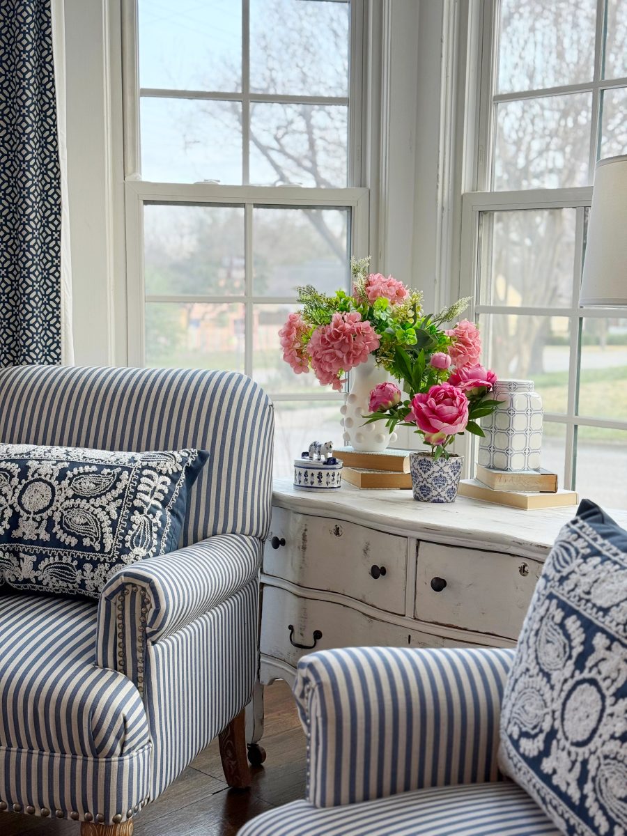 diy hobnail vase that looks like vintage milkglass 31 a cozy living room corner with blue and white striped armchairs, a white dresser, and a vase of pink flowers by large windows letting in natural light. patterned pillows and small decorative items add detail.