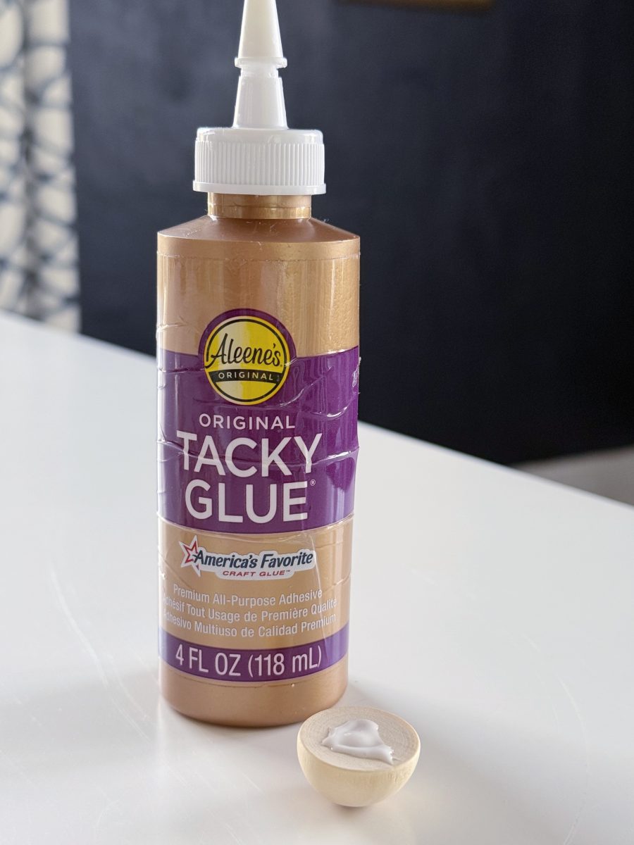 diy hobnail vase that looks like vintage milkglass 34 a bottle of aleene’s original tacky glue is on a white surface next to a small wooden bowl containing a dollop of glue. the bottle label is purple and brown, displaying product details.