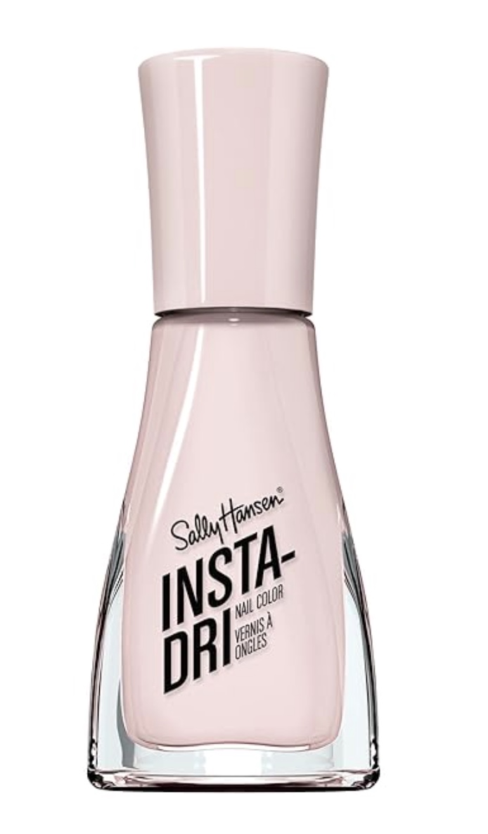 a bottle of sally hansen insta-dri nail color in a pale pink shade, with a tall pale pink cap and clear base showing the soft pastel polish inside. the label reads "insta-dri nail color.