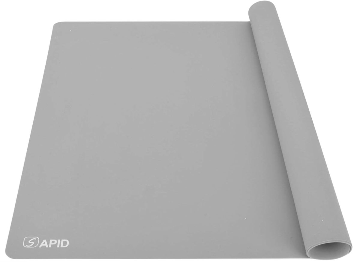 a large, light gray silicone mat partially rolled at one end, with the word "rapid" and its logo printed in white on the lower left corner. the mat is set against a plain white background.