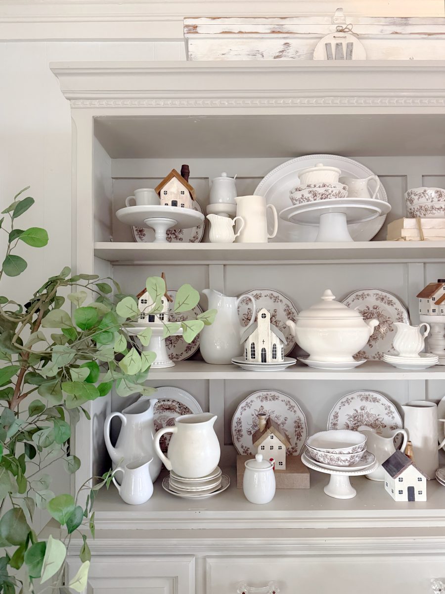 7 simple steps to style a hutch 38 style a hutch by displaying vintage-style white and floral dishes, teapots, pitchers, and miniature ceramic houses. a leafy green plant is positioned on the left side of the white hutch for a charming touch.