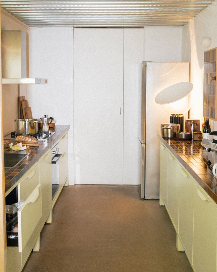 a wider view of the galley kitchen. the kitchen is lit by a taccia lamp design 23