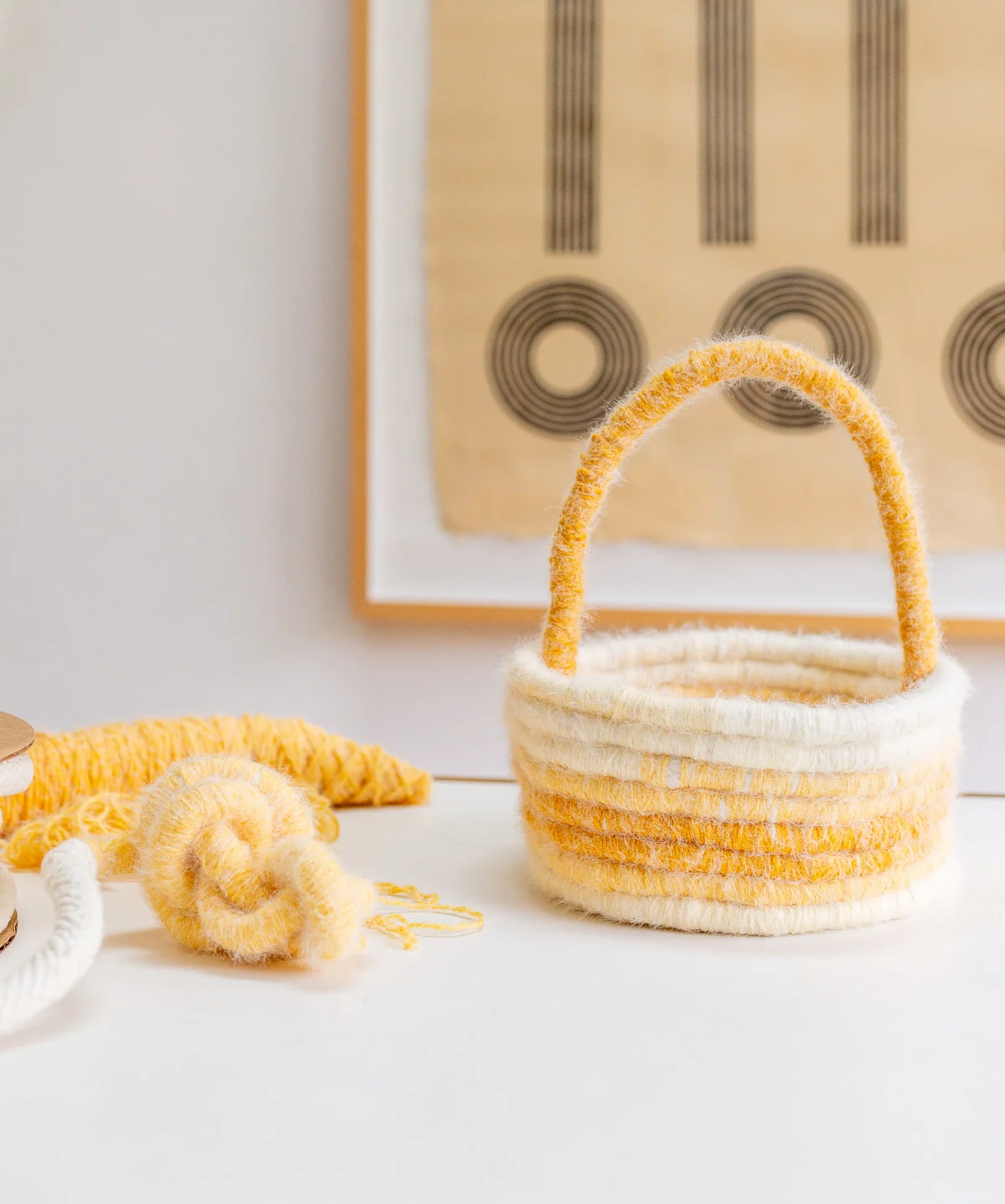 yellow easter basket made of yarn, sitting on a white table in a minimal dining room