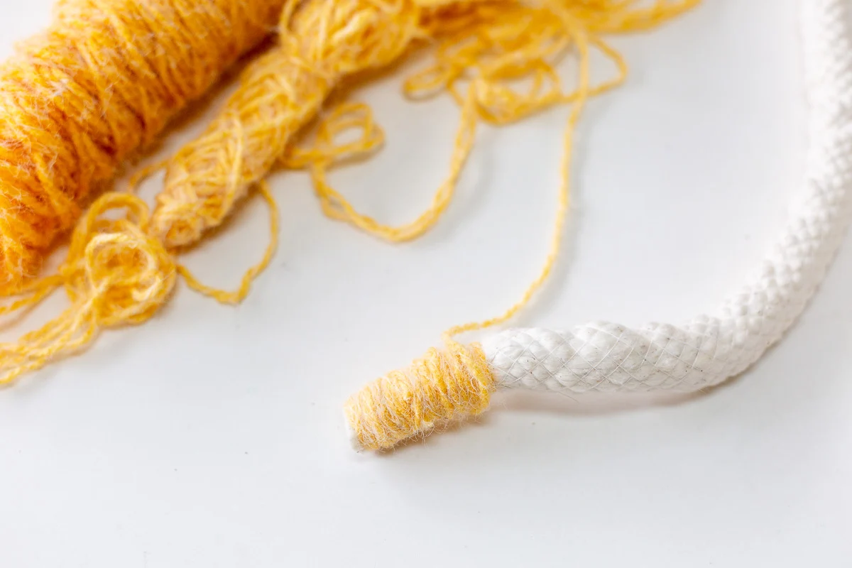 yellow yarn being wrapped around cotton cording over and over again