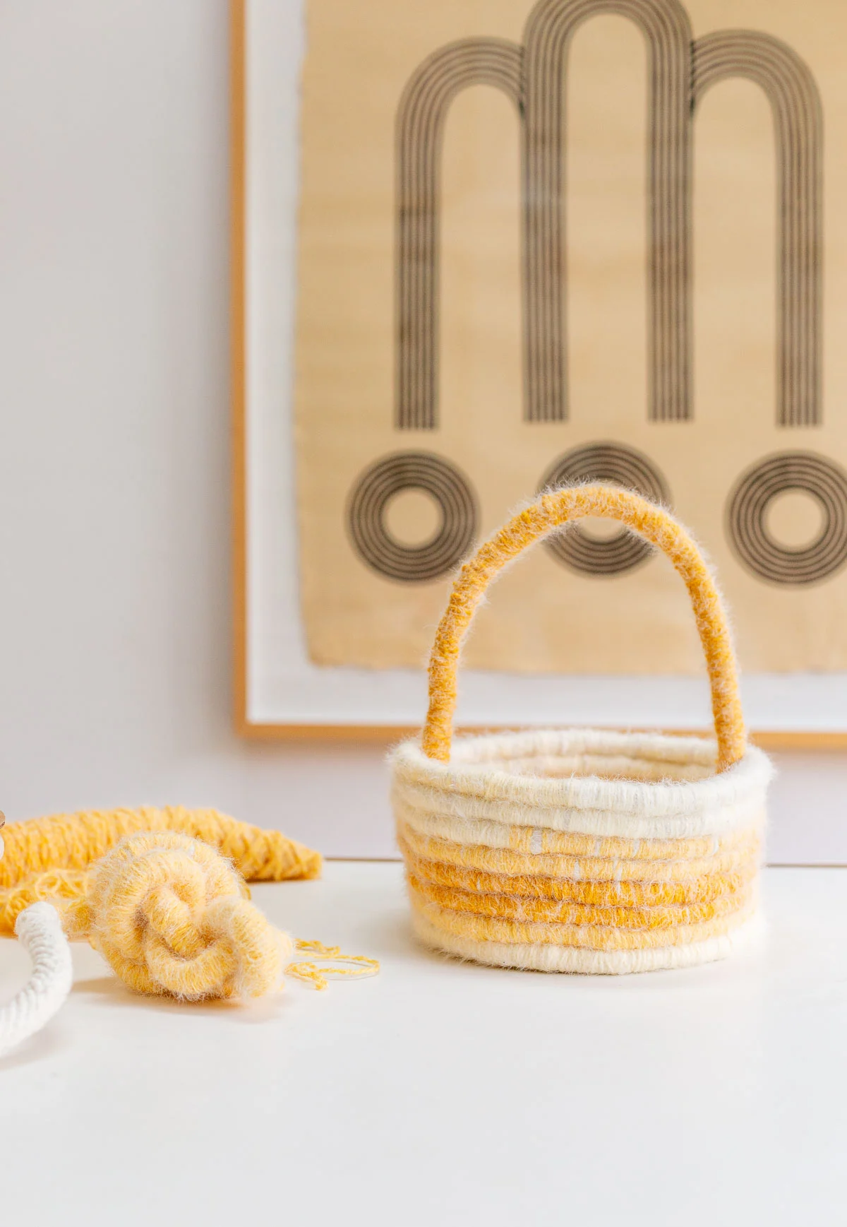 yellow easter basket sitting on white table with abstract art behind it