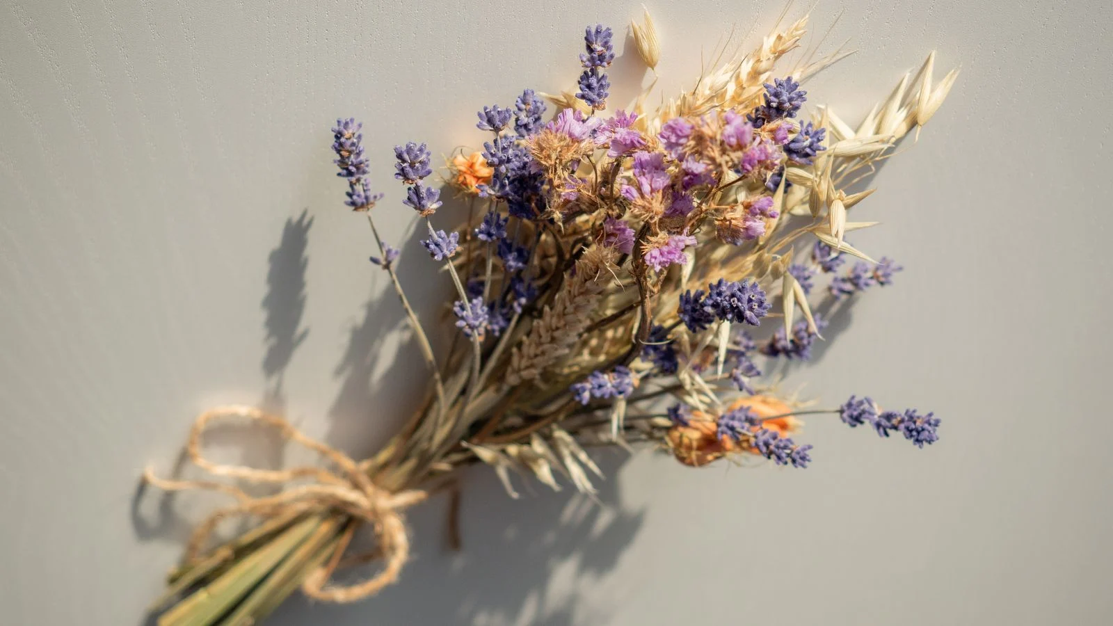 a close-up and overhead shot of an arrangement of fresh and dried blossoms, all placed on top of a white surface indoors