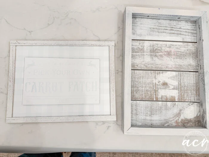 two rustic, white-washed wooden frames on a marble surface. the left frame has faint easter edition text about a carrot patch. the right frame has a slatted wood interior and is empty. flipping smalls acy logo appears in the corner.