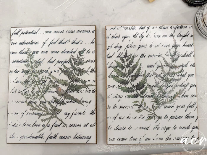 two rectangular canvases from the flipping smalls easter edition feature handwritten script in black ink and botanical fern illustrations on a white background, displayed side by side on a marble surface.