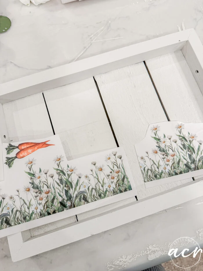 a white wooden tray being decorated with floral and carrot-themed paper cutouts, featuring daisies and carrots on a marble surface—perfect for your easter edition of flipping smalls.